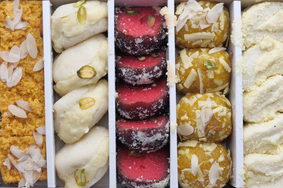 A vibrant collection of Indian sweets featuring almonds, pistachios, and coconut.